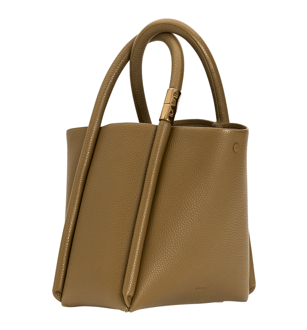 Brown, pebbled leather bag. Features oversized piping detail, an open top, intertwined handles, a subtle gold fastener, and a leather carrying strap.