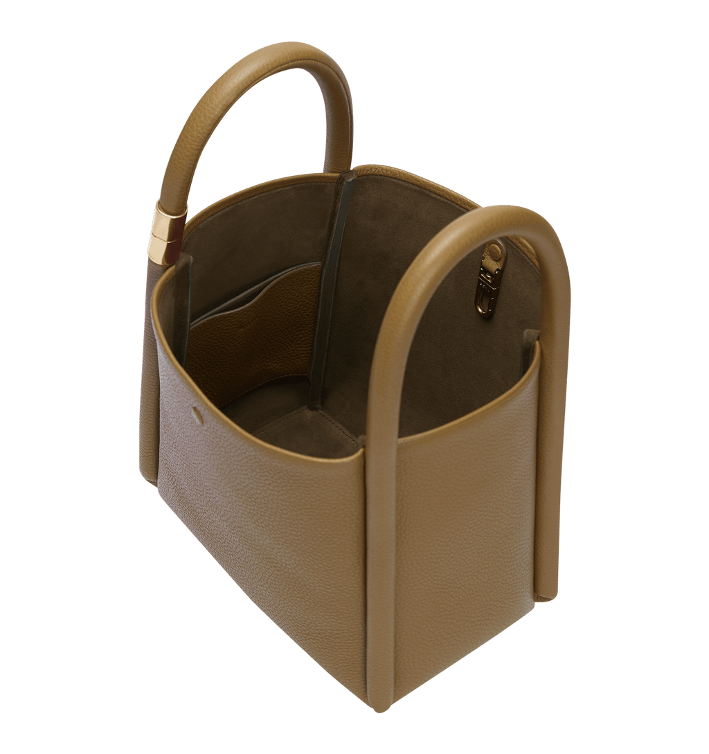 Brown, pebbled leather bag. Features oversized piping detail, an open top, intertwined handles, a subtle gold fastener, and a leather carrying strap.