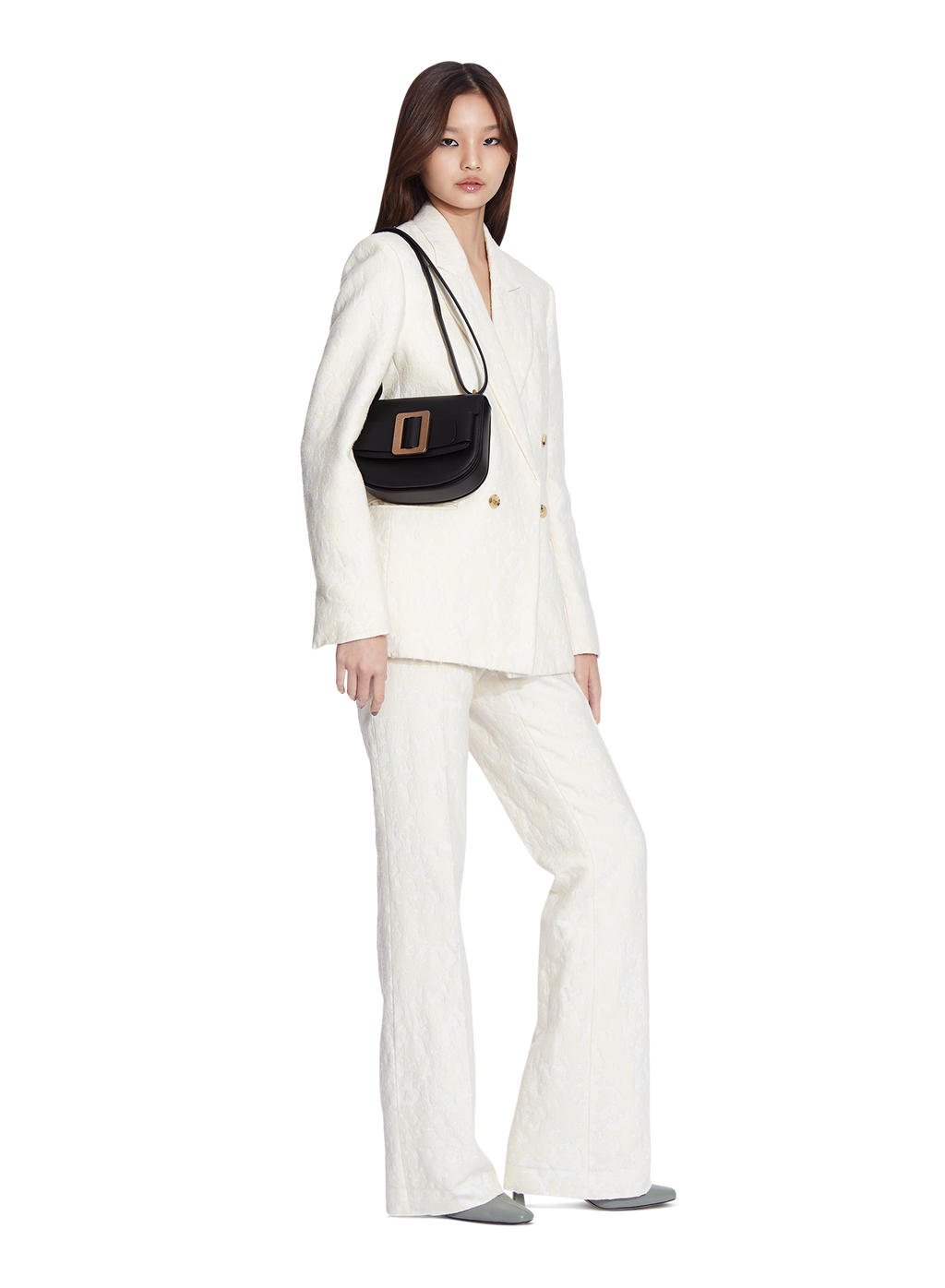 Black BOYY SADDLE bag made of palmellato calfskin leather, with a structured saddle-shaped silhouette, flap closure, adjustable shoulder-to-crossbody strap, and signature oversized buckle on model