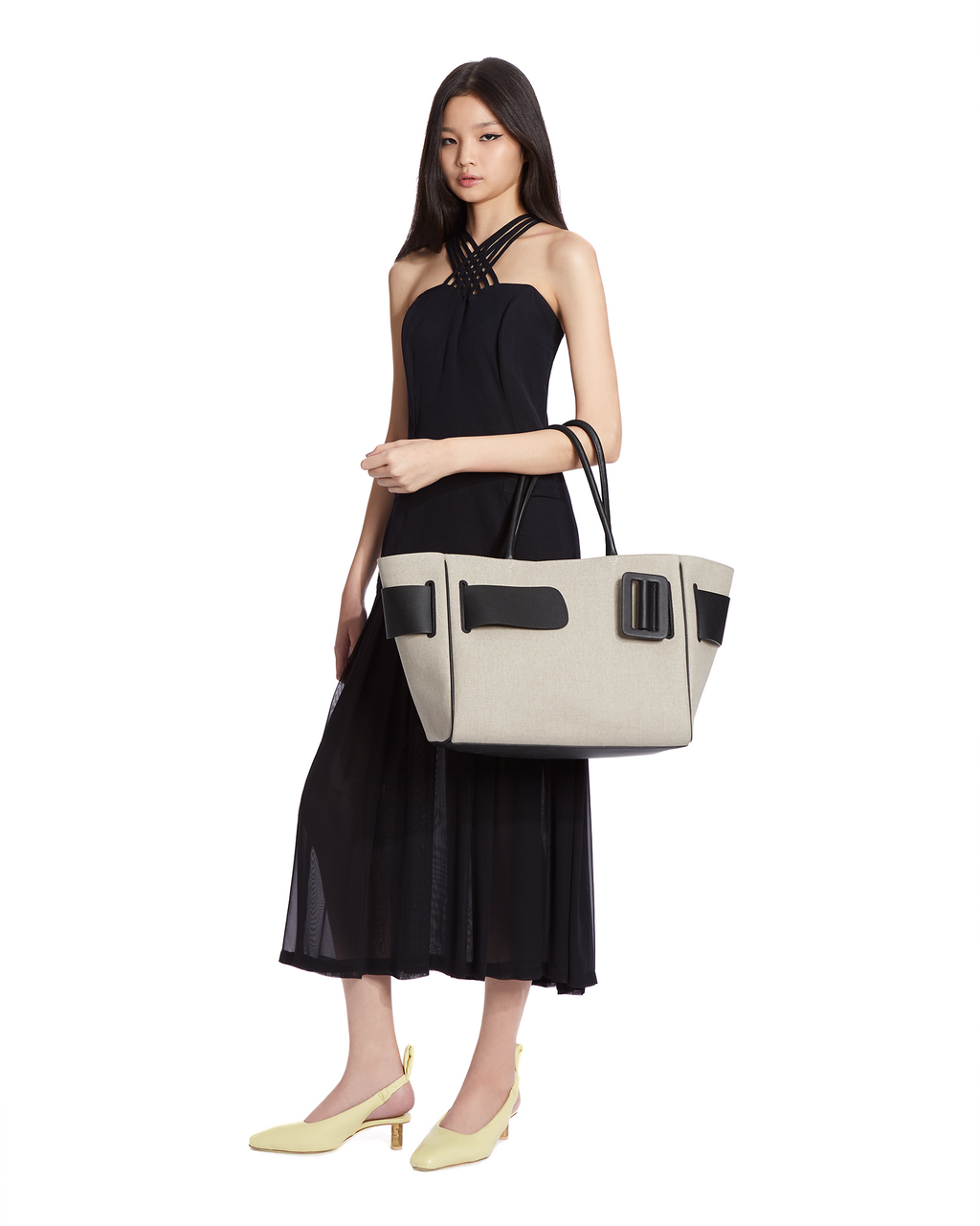 Natural Canvas BOYY BOBBY soft luxury handbag made of canvas. Features a relaxed, modern silhouette, extended over the shoulder handles with an oversized belt, buckle, and zipper closure on model