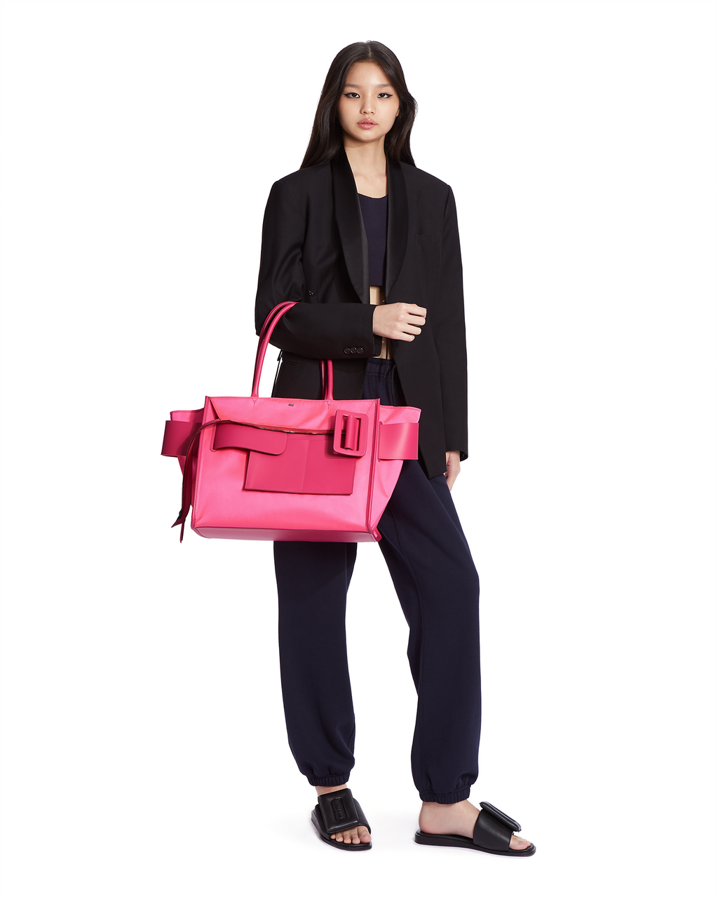 Neon pink BOYY BOBBY inside-out soft luxury handbag made of econyl nylon with calfskin leather. Features a relaxed, modern silhouette with an oversized belt, buckle, and zipper closure on model